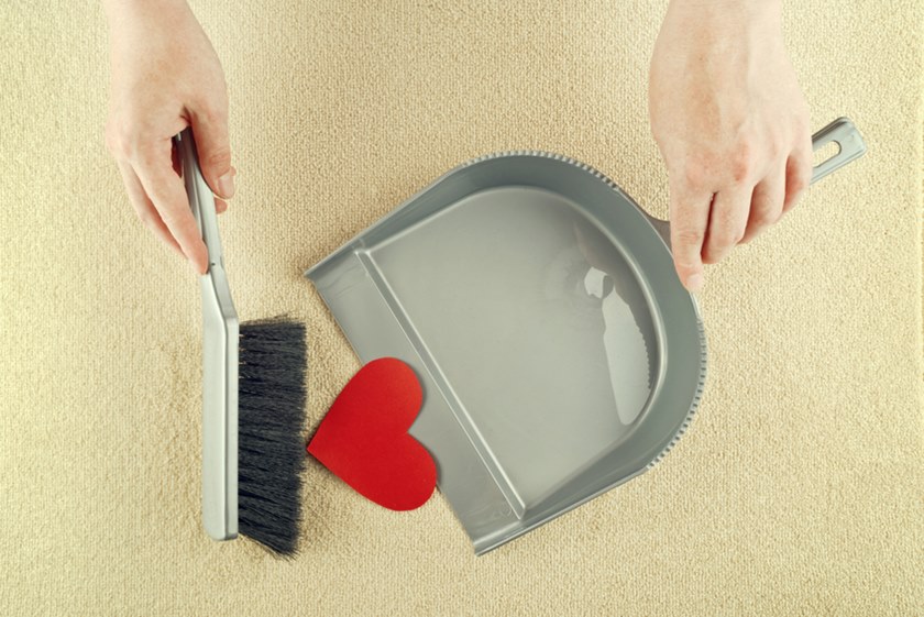 Hand sweeping heart from the floor with brush cleaner.